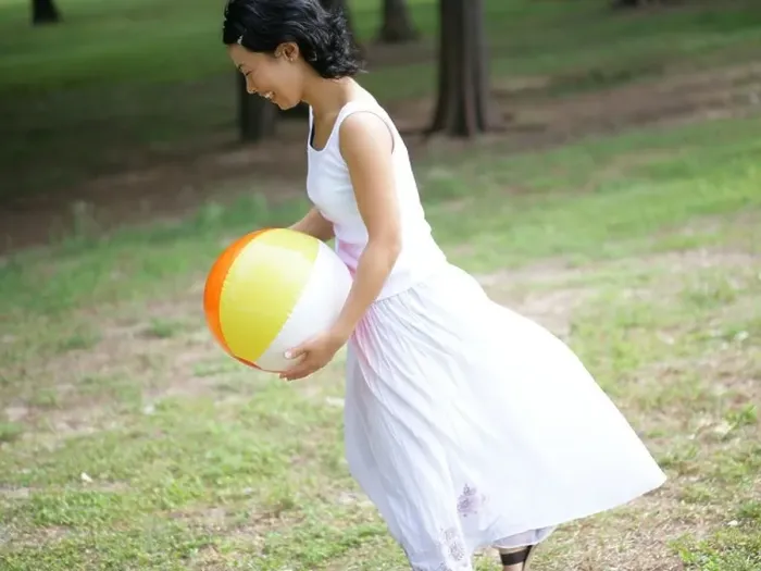 Framed Print : Side profile of a young woman holding a beach ball in a park Framed Print : Side profile of a young woman holding a beach ball in a park