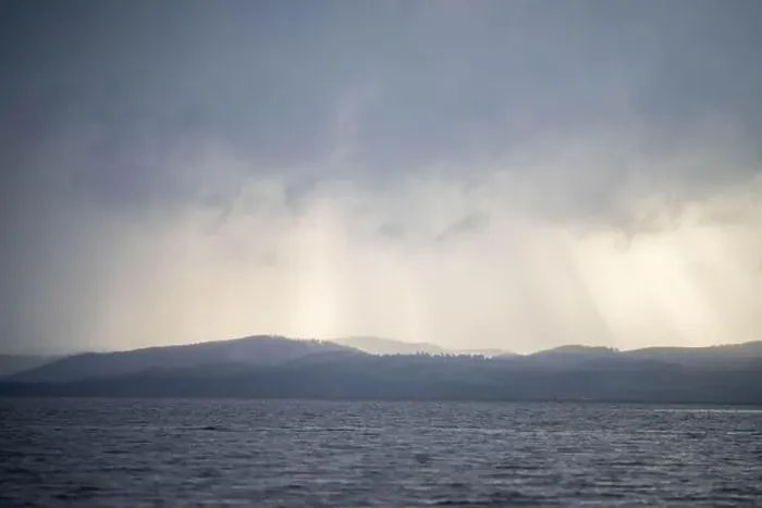 Framed Print : rays through clouds over the water