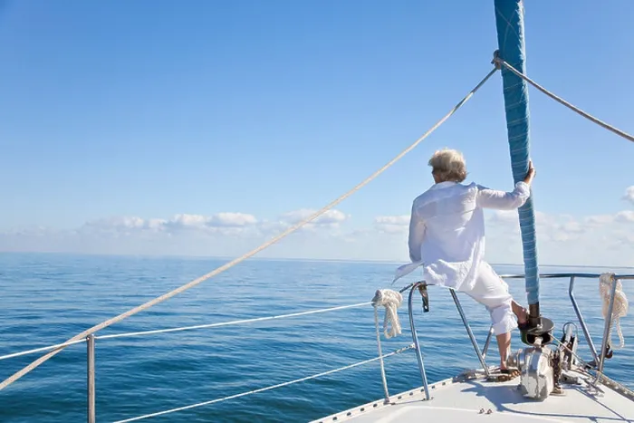 Framed Print : Rear view of a senior woman alone sitting on the front of a sail boat on a calm blue sea Framed Print : Rear view of a senior woman alone sitting on the front of a sail boat on a calm blue sea