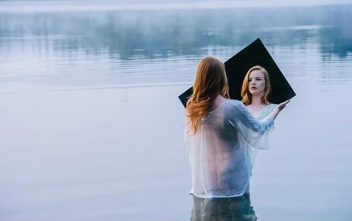 Framed Print : Rear view of young woman standing in lake holding mirror looking at reflection Framed Print : Rear view of young woman standing in lake holding mirror looking at reflection
