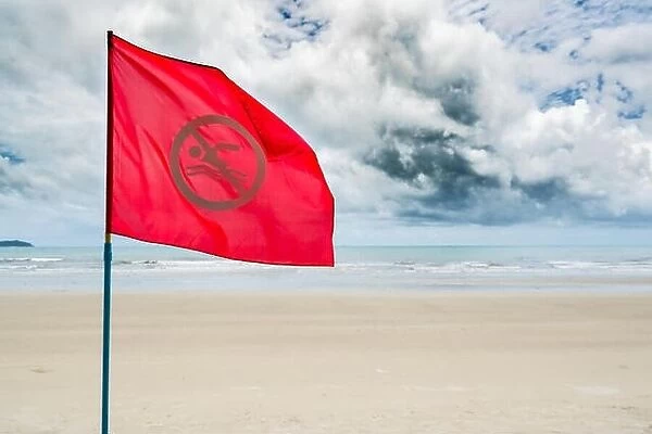 Red no swimming flag warning for tourist not to swim during storm coming in the sea