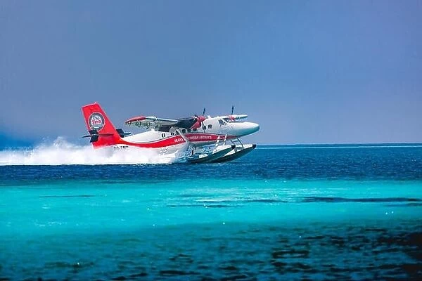 Red and white seaplane approaching island in the Maldives. Transmaldivian airlines in Maldives island