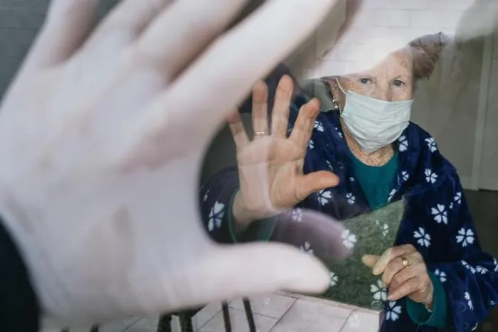 Framed Print : Redhead aged female in medical mask waving hand through window to relative while isolating at home Framed Print : Redhead aged female in medical mask waving hand through window to relative while isolating at home