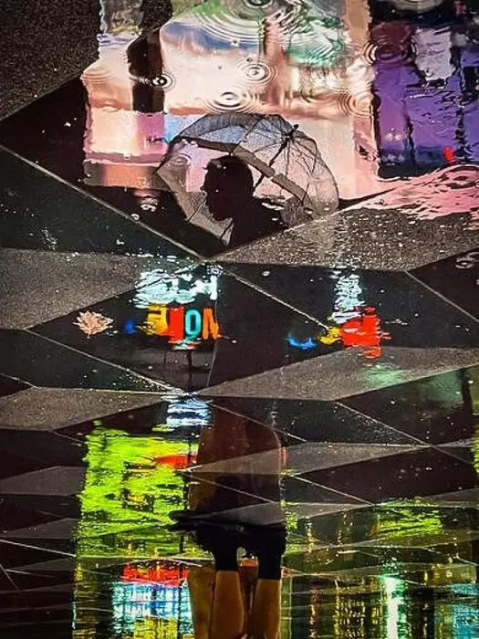 Framed Print : Reflection of a standing man holding an umbrella surrounded by colorful neon lights as seen in the reflection on wet Framed Print : Reflection of a standing man holding an umbrella surrounded by colorful neon lights as seen in the reflection on wet