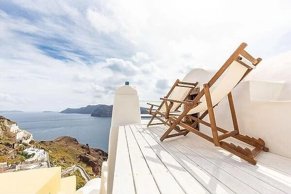Relax on Santorini. View on caldera and sea from balcony, Santorini, Greece. White resort terrace with chaise lounge concept. Cloudy morning in Oia