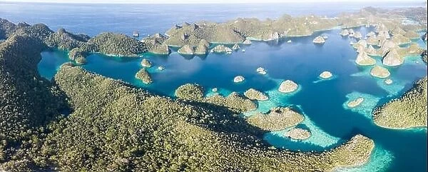 Remote limestone islands form a maze in a tropical lagoon in Raja Ampat, Indonesia. This diverse region is known as the heart of the Coral Triangle