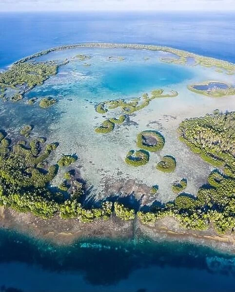 A remote tropical island in the Molucca Sea is fringed by mangrove forest surrounding a shallow lagoon. This island sits amid the Coral Triangle