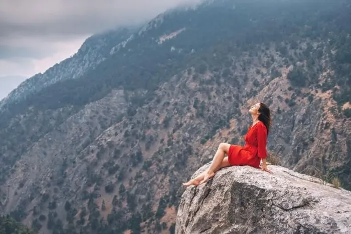Framed Print : Romantic aerial photo of a girl in a red dress on top of a cliff admiring the view of a mountain gorge