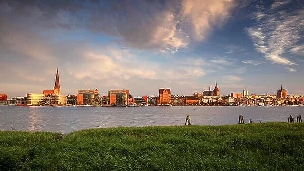 Rostock, Germany. Panoramic cityscape image of Rostock riverside with St. Peter's Church during summer sunset