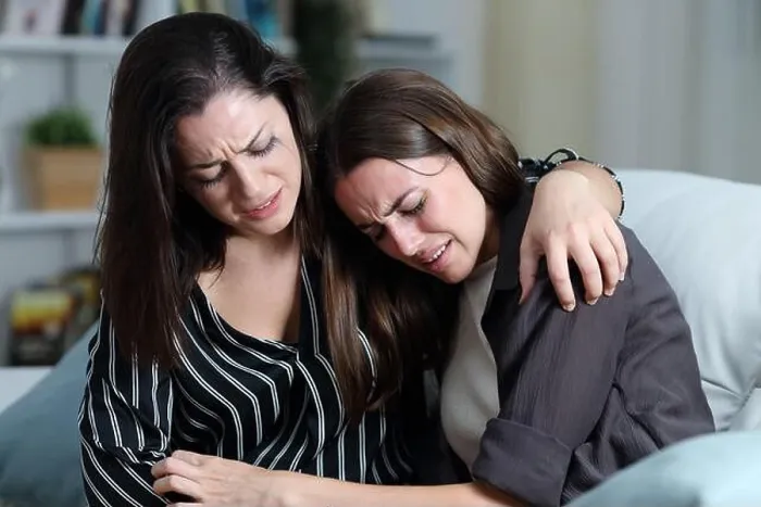 Framed Print : Two sad friends or sisters crying together on a couch in the living room at home Framed Print : Two sad friends or sisters crying together on a couch in the living room at home