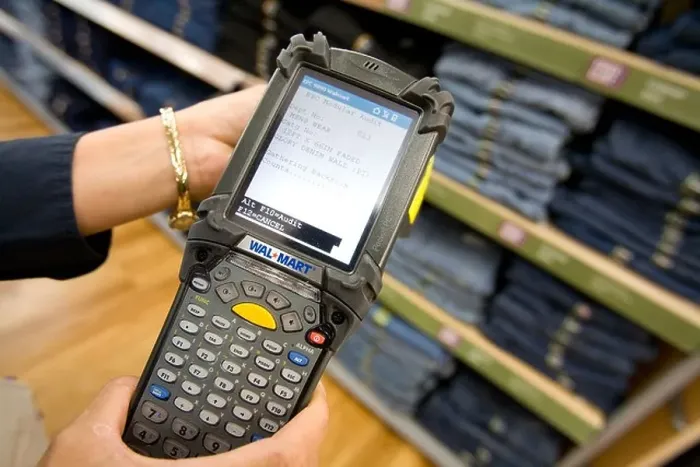 Framed Print : A sales associate uses a Telxon handheld scanner to read EPC / RFID labels on clothing at a Walmart Supercenter in Rogers Framed Print : A sales associate uses a Telxon handheld scanner to read EPC / RFID labels on clothing at a Walmart Supercenter in Rogers
