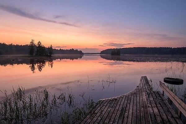 Scenic lake view with beautiful sunset, garbage and broken pier at summer night in Finland