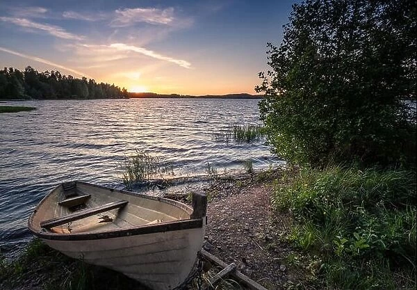 Scenic landscape with idyllic lake view and boat at summer evening in Finland