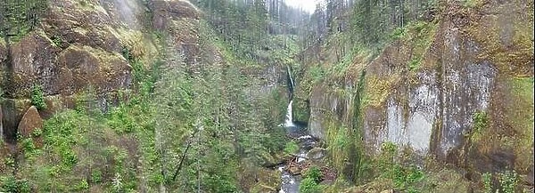 A scenic river flows over a waterfall and into the Columbia River Gorge, Oregon. This beautiful area is known for its waterfalls and forests