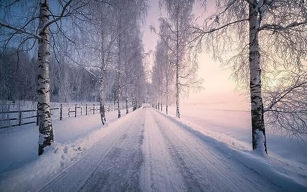 Scenic snow landscape with beautiful sunrise and snowy road at winter morning in Finland