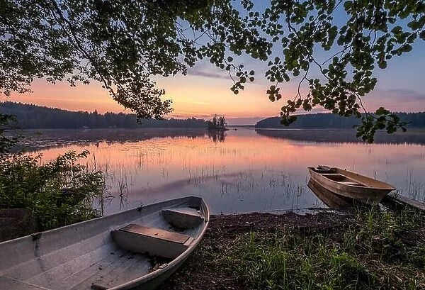 Scenic sunset view with two row boat and idyllic lake at summer night in Finland