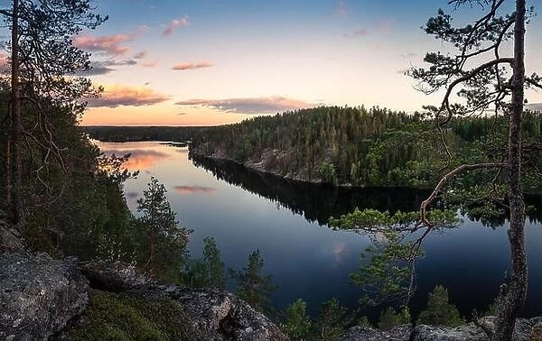 Scenic traditional Finnish landscape with lake and sunset at summer evening in Haukkavuori, Finland