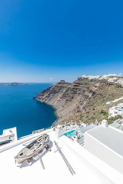 Scenic view of traditional cycladic resort with decoration boat foreground, Oia village, Santorini, Greece. Famous travel destination, luxury holiday