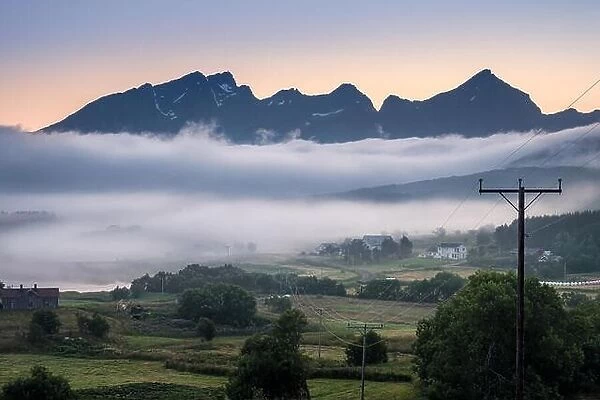 Scenic view from valley with mountain and hard fog at summer evening in Lofoten, Norway