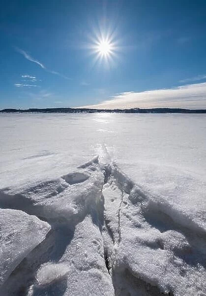 Scenic winter landscape with bright sunlight and sun at winter day in lake Finland