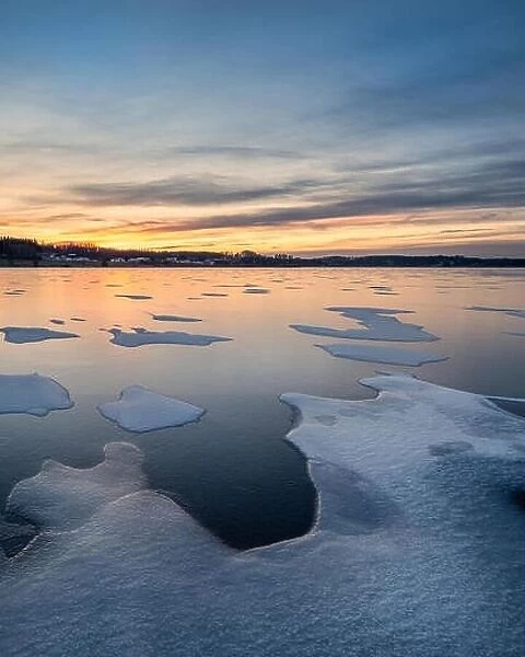 Scenic winter landscape with frozen lake, sunset and beautiful evening light in Finland