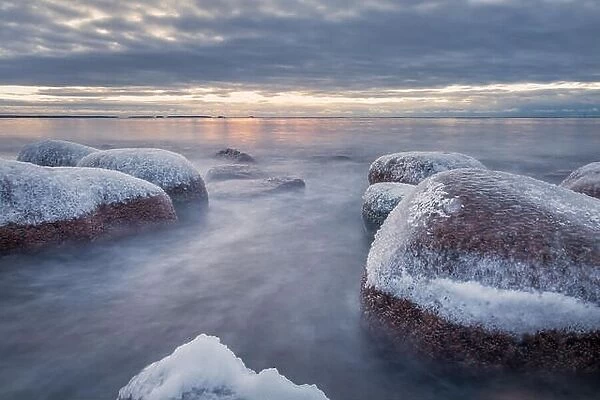 Scenic winter landscape with sea and sunrise at morning. Beautiful light with rocky coast in Finland