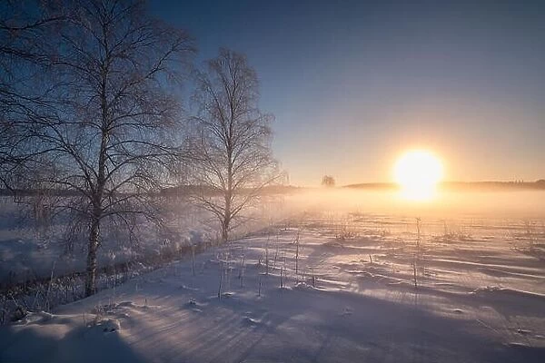 Scenic winter landscape with sunrise and fog at morning in Finland