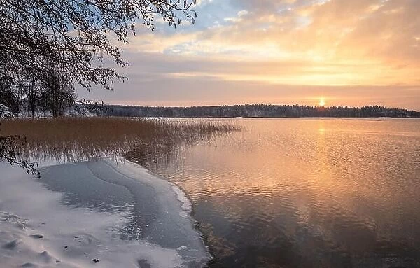 Scenic winter landscape with sunset at icy and peaceful lake in Finland