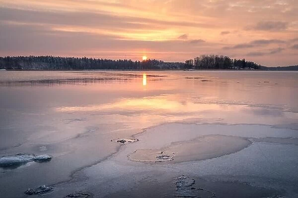 Scenic winter landscape with sunset and water reflections at evening time in Finland