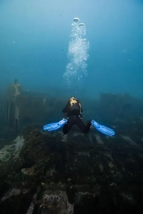Framed Print : A scuba diver with blue fins hovers near a sunken shipwreck enveloped in the tranquility of the underwater world Framed Print : A scuba diver with blue fins hovers near a sunken shipwreck enveloped in the tranquility of the underwater world