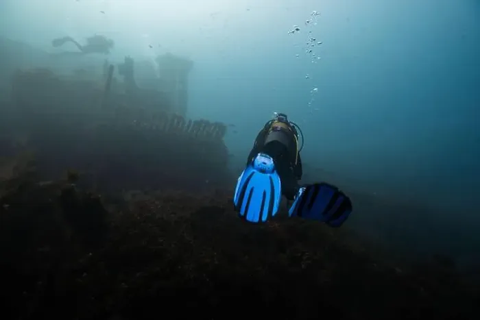 Framed Print : A scuba diver with blue fins investigates an eerie Framed Print : A scuba diver with blue fins investigates an eerie