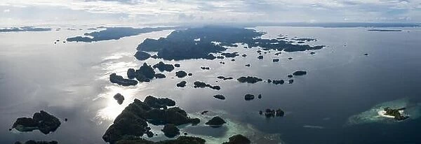Seen from above, remote islands are surrounded by coral reefs in Raja Ampat, Indonesia. This region is known as the heart of the Coral Triangle