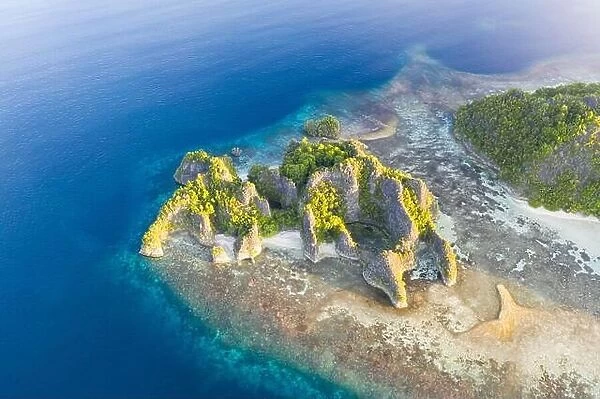 Seen from an aerial view, the tropical Pacific Ocean surrounds the rugged limestone islands scattered throughout the amazing seascape of Raja Ampat