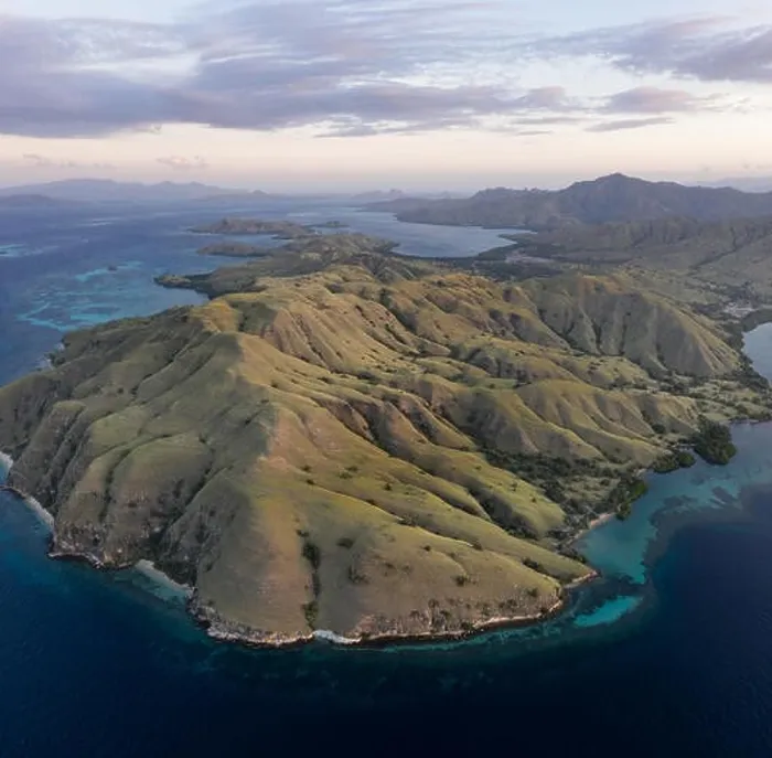 Framed Print : Seen from a bird's eye view, the blue Pacific Ocean surrounds the rugged island of Komodo in Indonesia. This tropical area is known for its diversity Framed Print : Seen from a bird's eye view, the blue Pacific Ocean surrounds the rugged island of Komodo in Indonesia. This tropical area is known for its diversity