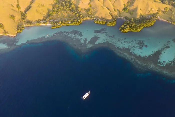 Framed Print : Seen from a bird's eye view, an idyllic island is surrounded by a healthy coral reef in Komodo National Park, Indonesia Framed Print : Seen from a bird's eye view, an idyllic island is surrounded by a healthy coral reef in Komodo National Park, Indonesia
