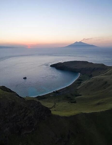 Seen from a bird's eye view, an idyllic, tropical island, Gili Banta, is lit by the setting sun just outside of Komodo National Park, Indonesia