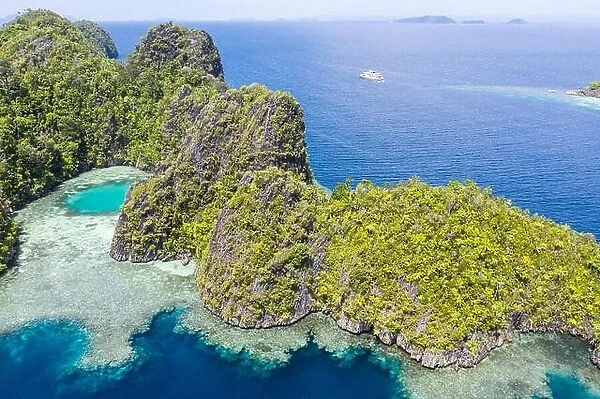 Seen from a bird's eye view, limestone islands rise from Raja Ampat's calm seascape. This tropical area is known for its amazing marine biodiversity