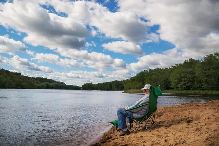 Framed Print : Senior man sitting by the river fishing Framed Print : Senior man sitting by the river fishing