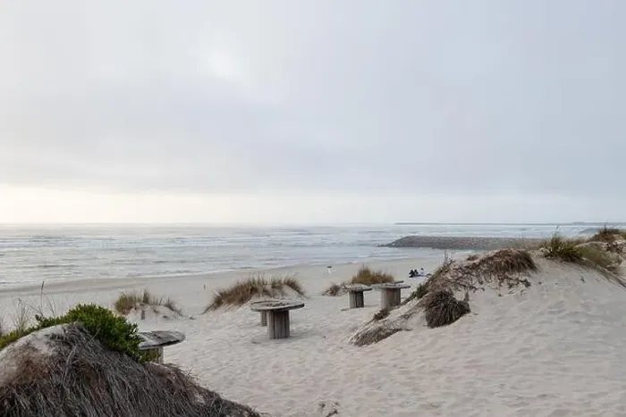Framed Print : A serene beach with dunes and views of a calm ocean under a cloudy late-day sky Framed Print : A serene beach with dunes and views of a calm ocean under a cloudy late-day sky