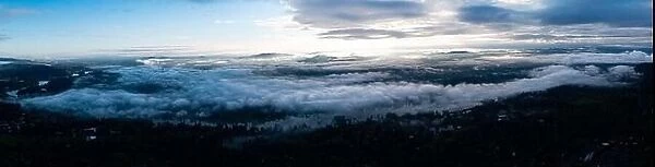 A serene panoramic sunrise illuminates low clouds and fog over the Willamette River south of Portland, Oregon