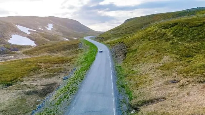 Framed Print : A single car drives along a winding road through a green Framed Print : A single car drives along a winding road through a green