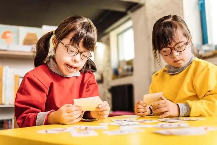 Framed Print : Sisters with Down syndrome playing with cards together Framed Print : Sisters with Down syndrome playing with cards together