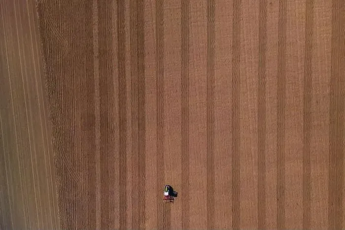 Framed Print : A small lonely tractor with plow on a large brown field with plowed earth seen directly from above Framed Print : A small lonely tractor with plow on a large brown field with plowed earth seen directly from above