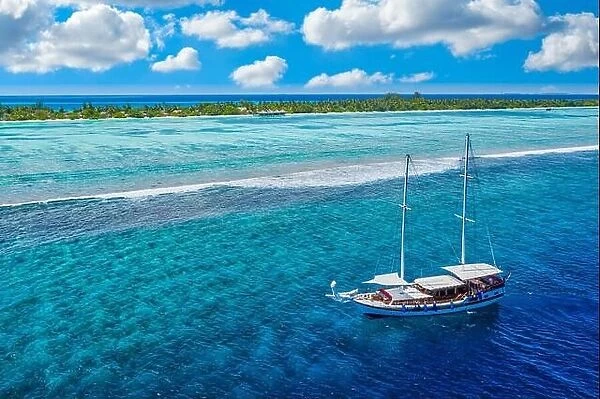 Small yacht sailing tropical sea over coral reef in Indian ocean lagoon. Exotic island landscape aerial view, stunning nature scenic freedom adventure