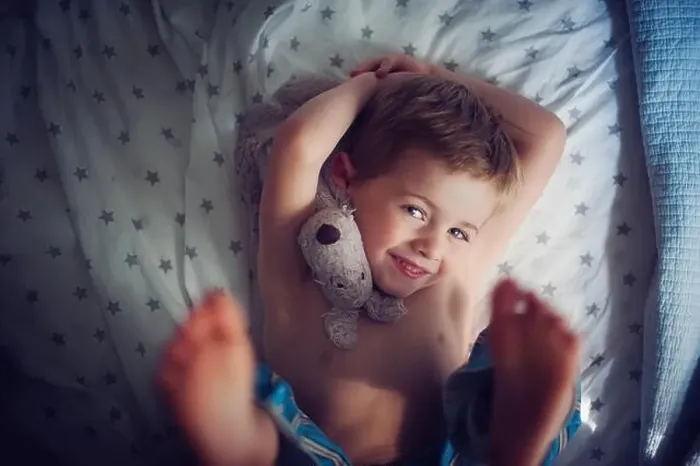 Framed Print : Smiling Boy lying on bed with cuddly toy Framed Print : Smiling Boy lying on bed with cuddly toy