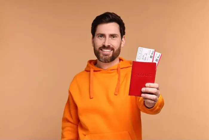 Framed Print : Smiling man showing passport and tickets on beige background Framed Print : Smiling man showing passport and tickets on beige background