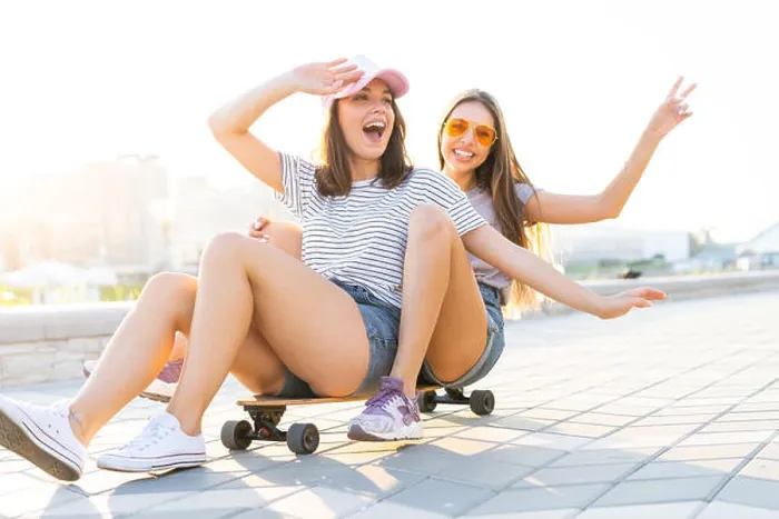 Framed Print : Two smiling young girls having fun while riding on a skateboard at the park Framed Print : Two smiling young girls having fun while riding on a skateboard at the park