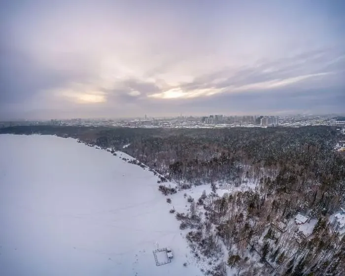 Framed Print : Snow-covered forest on lake shore with ice at sunset and the city on horizon Framed Print : Snow-covered forest on lake shore with ice at sunset and the city on horizon