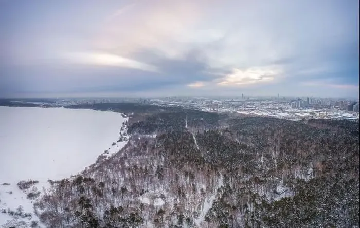 Framed Print : Snow-covered forest on lake shore with ice at sunset and the city on horizon Framed Print : Snow-covered forest on lake shore with ice at sunset and the city on horizon
