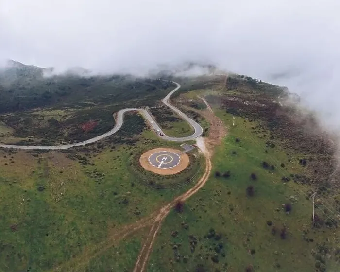 Framed Print : Spectacular drone view of curved serpent road near round concrete helipad on grassy rural valley on summer day running